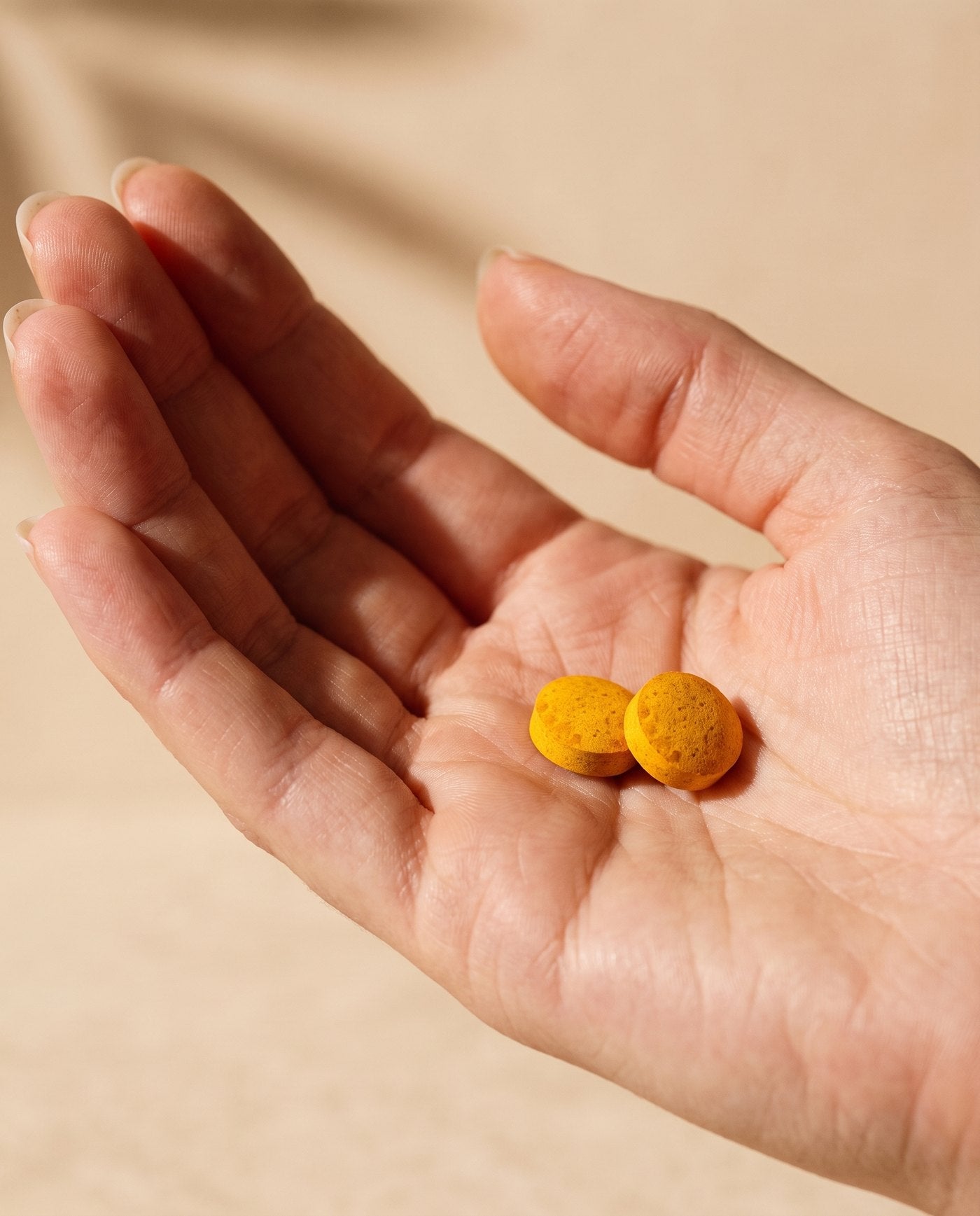 Two AYA BIOME™ chewable tablets in an open palm
