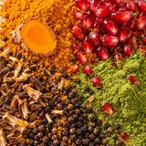 Turmeric, pomegranate seeds, green matcha powder and black peppercorns spread side by side