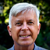 Alastair Jessel, founder, smiling outdoors in front of green leaves