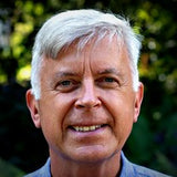 Alastair Jessel, founder, smiling outdoors in front of green leaves